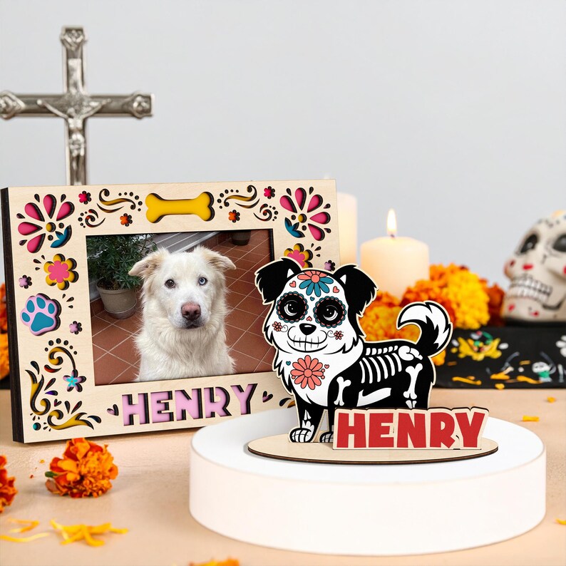 May include: A wooden photo frame with a dog picture and the name "HENRY" in pink letters. A decorative dog figurine with a skeleton design and the name "HENRY" is also present. The theme is Day of the Dead.