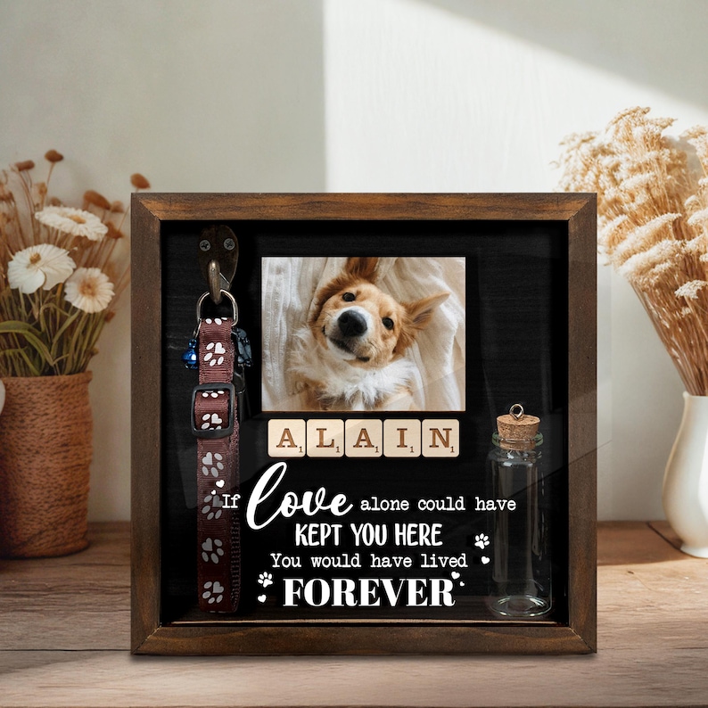 May include: A wooden shadow box with a photo of a dog, scrabble tiles spelling "ALAIN", and a brown dog collar. The text reads "If love alone could have kept you here, you would have lived forever."