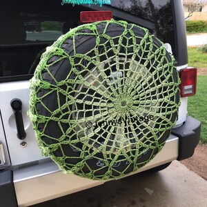 May include: A lime green crocheted spare tire cover on a vehicle. The cover has a circular, web-like design. The tire is mounted on the back of a silver SUV. The Etsy shop name "Jenny's Vintage" is visible in the image.