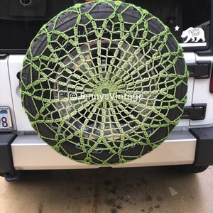 May include: A lime green crocheted spare tire cover on a black tire. The cover has a web-like design and is mounted on the back of a white SUV. The Etsy shop name "JennysVintage" is visible in the image.