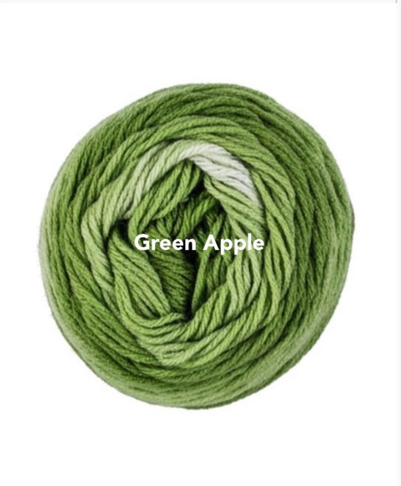 May include: A ball of Green Apple yarn, a blend of green shades, is tightly wound. The yarn is labeled with the text "Green Apple". This yarn is suitable for knitting and crochet projects.