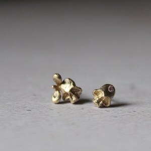 Peut inclure: Deux boucles d'oreilles en forme de cr&acirc;ne en or, l'une avec une petite pierre rose dans l'orbite.