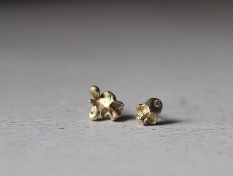 Peut inclure: Deux boucles d'oreilles en forme de cr&acirc;ne en or, l'une avec une petite pierre rose dans l'orbite.