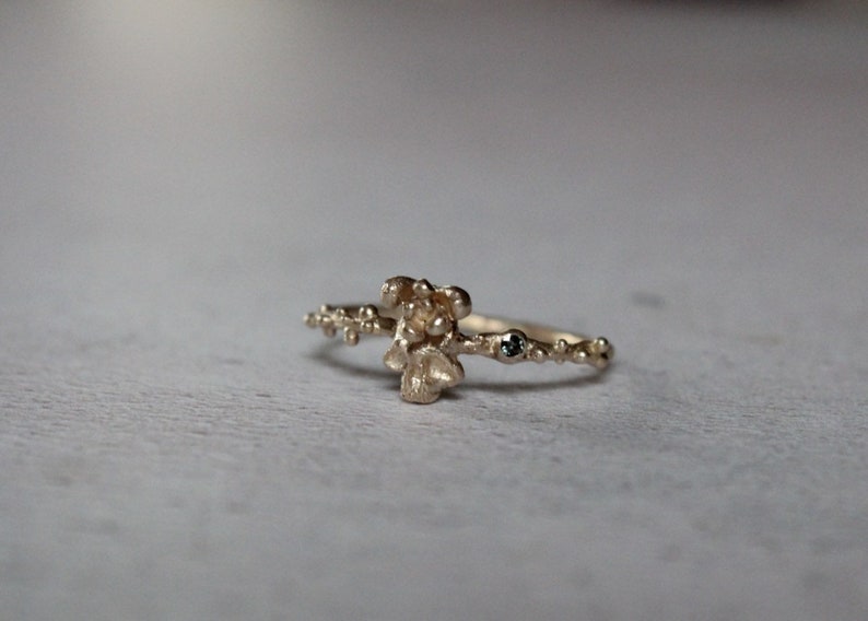 May include: A gold ring with a textured, organic design and small blue gemstones.