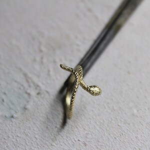 May include: A gold snake ring with a textured finish. The snake is coiled around the ring band.
