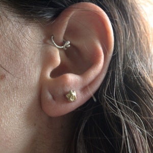 Peut inclure: Gros plan sur une oreille avec un petit piercing en or et un anneau en argent dans le cartilage sup&eacute;rieur.