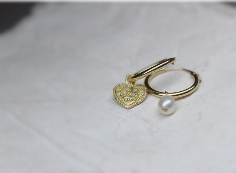 May include: Gold hoop earrings with a heart charm that says "Forever and Always" and a pearl dangle charm.