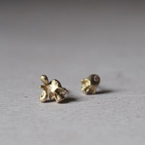 Peut inclure: Une paire de boucles d'oreilles en forme de cr&acirc;ne en or. L'une des boucles d'oreilles a une petite pierre rose dans l'orbite de l'&oelig;il.