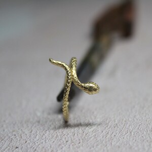 May include: A gold-colored snake ring with a textured surface. The snake is curled up with its head facing forward.