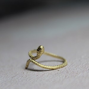 May include: A gold-colored snake ring with a textured finish. The snake is curled up with its head raised.