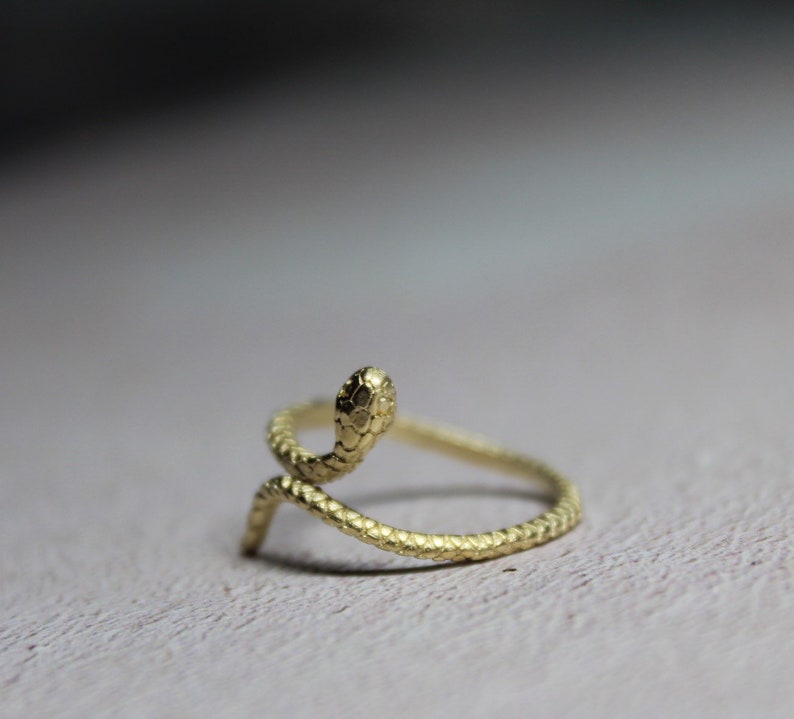 May include: A gold-colored snake ring with a textured finish. The snake is curled up with its head raised.