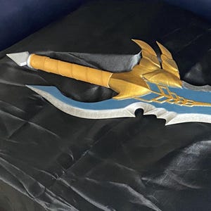 May include: A blue and gold fantasy sword with a decorative handle. The sword has a sharp point and a curved blade.