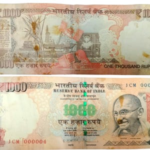 May include: A 1000 Indian Rupee banknote shown from both sides. The front features a portrait of Mahatma Gandhi, the text Reserve Bank of India, and the denomination 1000. The back displays an industrial scene with an oil rig and a satellite.