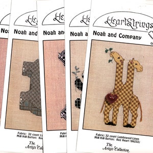 May include: A stack of cross-stitch pattern packets from HeartStrings, featuring designs of giraffes, elephants, and other animals. The packets include fabric and button details. The text "Noah and Company" and "The Artists Collection" are visible.