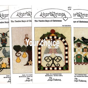 May include: Four cross-stitch patterns from the HeartStrings collection, featuring the Twelve Days of Christmas. The patterns include a nutcracker, a pear tree, two turtle doves, and four calling birds. Each pattern is printed on a white background with a red heart logo and the title "The Artists Collection."