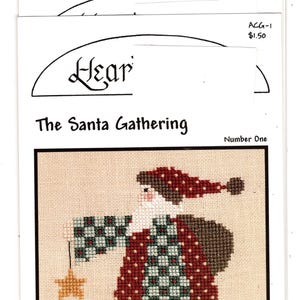 May include: Cross-stitch pattern titled "The Santa Gathering" featuring a cross-stitched Santa Claus holding a star ornament and a peppermint candy button. The Santa Claus is wearing a red and green outfit. The pattern is on antique white fabric.
