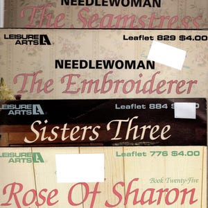 May include: Four vintage Leisure Arts needlework books with floral patterned covers. The titles are "The Seamstress", "The Embroiderer", "Sisters Three", and "Rose of Sharon". Each book has a price and leaflet number listed.
