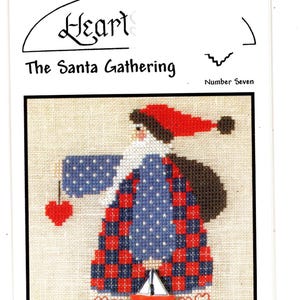 May include: Cross-stitch pattern featuring a Santa Claus design. Santa wears a red and blue checkered coat, a red hat, and holds a red heart. The text "Heart The Santa Gathering" is above the image. The Artists Collection.