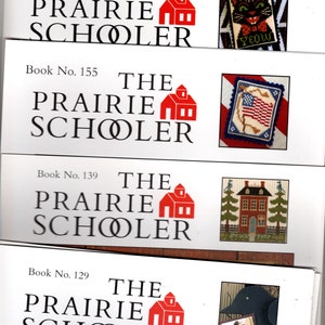 May include: Four white cards with red and black text, each with a red schoolhouse graphic and the text "The Prairie Schooler" and a book number. Each card also has a small image of a different cross-stitch design.