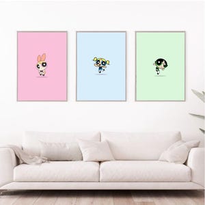 以下が含まれることがあります： パワーパフガールズのフレーム入りプリント3枚。それぞれ異なるキャラクター、ブロッサム、バブルス、バターカップが描かれています。プリントはそれぞれ、薄いピンク、薄いブルー、薄いグリーンの背景になっています。