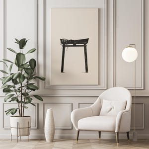 May include: A black and white illustration of a traditional Japanese torii gate, a gateway to a Shinto shrine, printed on a beige canvas. The canvas is framed and hanging on a white wall in a room with a white armchair and a floor lamp.