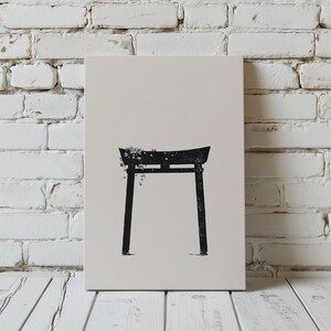May include: A black and white illustration of a traditional Japanese torii gate with a floral design on top. The gate is set against a white brick wall background.