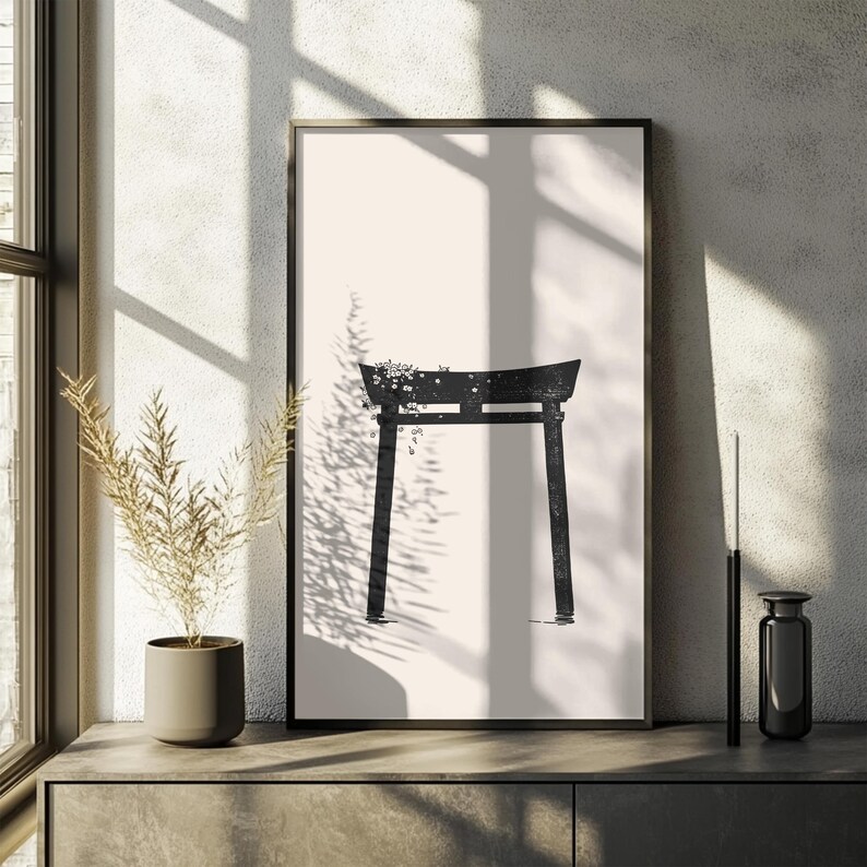 May include: Black and white minimalist print of a traditional Japanese torii gate with a floral design. The print is framed and hanging on a wall.