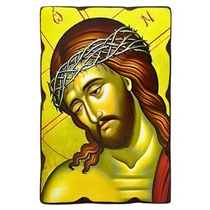 Può includere: Un'icona religiosa rettangolare raffigurante un ritratto dipinto di una figura con lunghi capelli castani e barba, che indossa una corona di spine. Lo sfondo è giallo vibrante con sottili linee rosse e lettere greche negli angoli superiori.