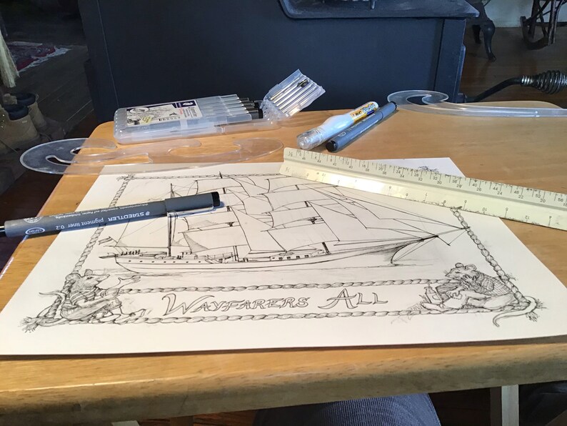 May include: A black and white drawing of a ship with the text "Wayfarers All" on a white sheet of paper. The drawing is surrounded by a rope border. A ruler and a black pen are on the table next to the drawing.
