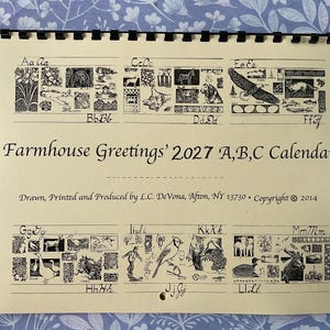May include: A spiral-bound 2027 calendar titled Farmhouse Greetings 2027 A,B,C Calendar. The cream-colored page features black ink illustrations of animals and objects corresponding to letters A through M, with copyright text by L.C. DeVona.