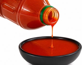 May include: A clear plastic bottle with a green cap pouring a vibrant orange-red liquid sauce into a matte black bowl. The sauce is viscous and flows in a single steady stream from the bottle opening into the centre of the bowl.