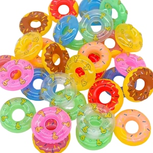 May include: A collection of colorful inflatable donut-shaped pool floats. The floats feature various colors, including pink, yellow, green, blue, and brown, with a duck pattern. These floats are designed for water fun and relaxation.