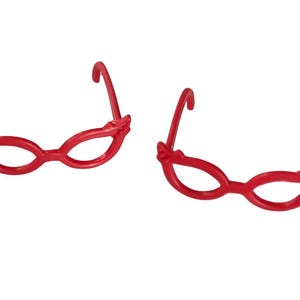 May include: Two pairs of red plastic cat eye glasses.