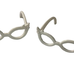 May include: Two pairs of white, decorative eyeglasses with a whimsical design. The frames have a rounded shape with decorative accents near the temples. The glasses are set against a plain white background.