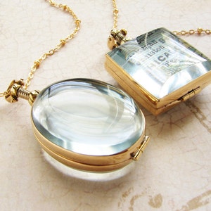 May include: Two gold chain necklaces with antique-style lockets. One locket is round and has a magnifying glass lens. The other locket is square and has a piece of paper inside.