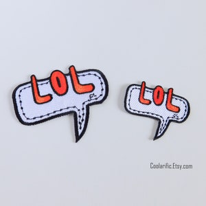 Puede incluir: Dos parches de burbujas de diálogo blancas con contornos negros y texto "LOL" rojo. El parche más grande es ligeramente más grande que el parche más pequeño.