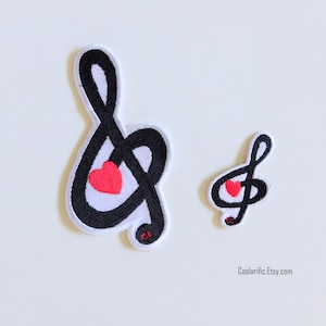 May include: Two iron-on patches featuring a black treble clef with a red heart inside. The larger patch is about 2 inches tall and the smaller patch is about 1 inch tall.