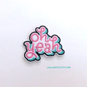May include: Pink and blue embroidered iron-on patch with the text "Oh yeah" in a retro font.