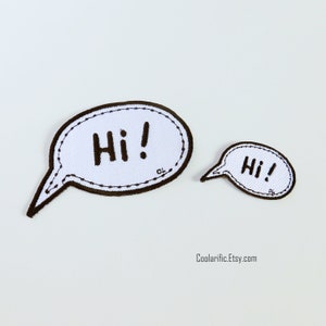May include: Two white speech bubble patches with black outlines and the word "Hi!" in black. The larger patch has a longer tail and a dotted border. The smaller patch is a miniature version of the larger one.