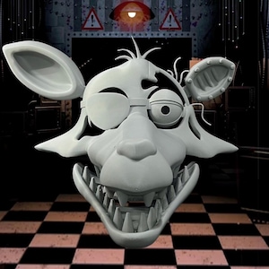 Könnte beinhalten: Eine hellgraue, 3D-gedruckte Maske eines fuchsartigen Charakters mit offenem Mund und scharfen Zähnen. Die Maske hat eine Augenklappe und detaillierte Merkmale, einschließlich Ohren und Gesichtszügen. Der Hintergrund zeigt einen karierten Boden und industrielle Elemente.