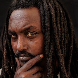 Foto artistica, rifugiato, insolito ritratto di strada, ragazzo moro con i dreadlocks,