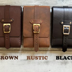 May include: Three leather pouches with a buckle closure. The pouches are brown, rustic brown, and black.