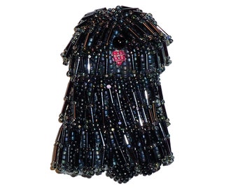 May include: A black beaded dog figurine with a red heart on its chest. The figurine is made of small, black beads and has a shaggy, fluffy appearance.