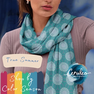 May include: A teal blue scarf with a white circle pattern. The scarf is worn by a person with a light purple shirt. The text "True Summer" is in a white oval shape. Below the text is a rainbow-colored bar with the text "Shop by Color Season". The text "Ceruleo Colour Works" is in a white oval shape with a blue wave design.
