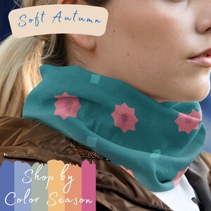 May include: A teal blue neck gaiter with a pink star pattern. The text "Soft Autumn" is written in white on a beige background above the neck gaiter. The text "Shop by Color Season" is written in white on a colorful striped background below the neck gaiter.