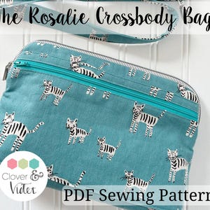 May include: A teal crossbody bag with a zipper closure and a strap. The bag is patterned with white and black tiger illustrations. The text "The Rosalie Crossbody Bag" is at the top, and "PDF Sewing Pattern" is at the bottom.