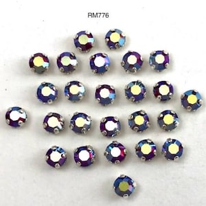 May include: A collection of 25 iridescent blue and purple rhinestones with silver settings. The rhinestones are arranged in a circular pattern on a white background. The text "RM776" is printed in black at the top of the image.