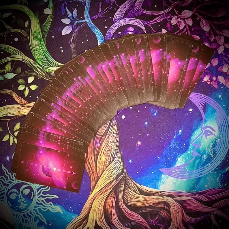 Pode incluir: Um baralho de cartas de tarot em leque, exibindo um design c&oacute;smico com tons rosa e roxo. As cartas s&atilde;o colocadas em um fundo de &aacute;rvore da vida e lua crescente, evocando um tema m&iacute;stico.