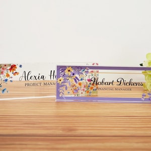 Peut inclure: Deux plaques de nom de bureau en acrylique avec des motifs floraux. La plaque supérieure indique "Alexia H. Project Manager". La plaque inférieure indique "Hobart Dickens Financial Manager".