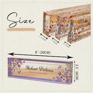 May include: A floral-themed desk nameplate with the name "Hobart Dickens, Financial Manager" in elegant script. The nameplate is 8 inches (20 cm) long and 2.5 inches (6 cm) high, with a purple border and floral accents. Additional nameplates are visible.
